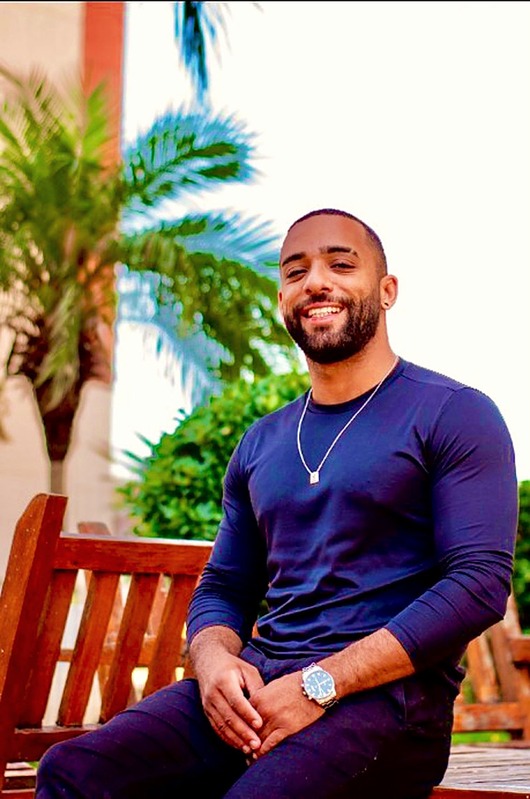 Felipe Pereira sorrindo, sentado num banco